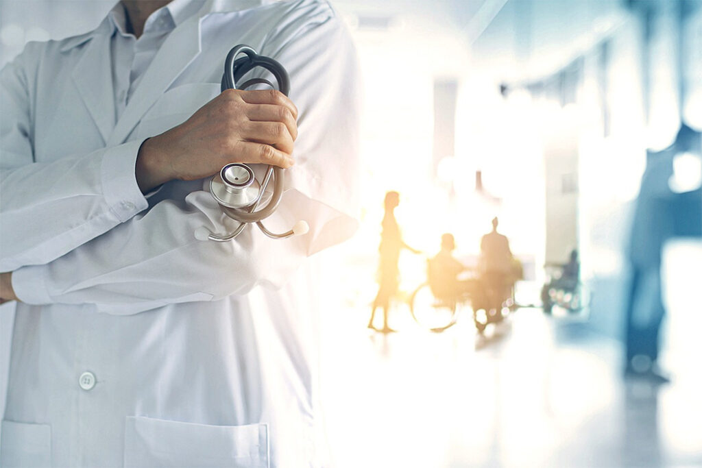 Medizin Köln Fotostudio - Arzt steht im Vordergrund. Im Hintergrund sind Menschen zu sehen.